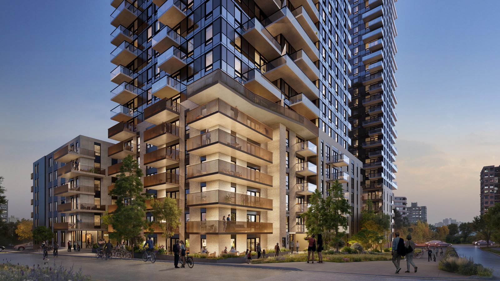 A mixed-use residential development at dusk, showing a brick-clad podium with retail at grade and a glazed tower above